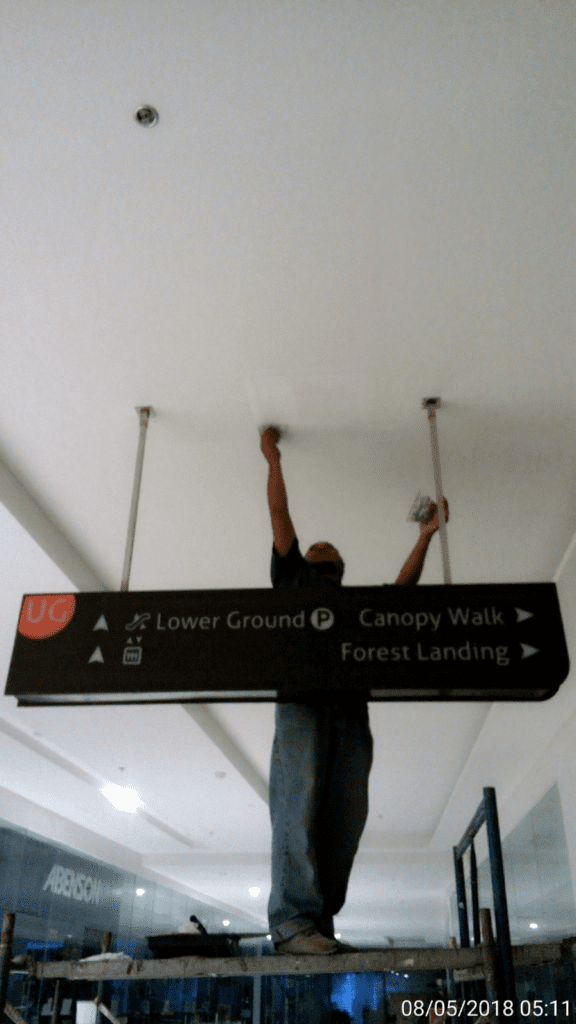 Installing indoor wayfinding signage for Lower Ground, Canopy Walk in Quezon City corridor by M&G Global Ads.